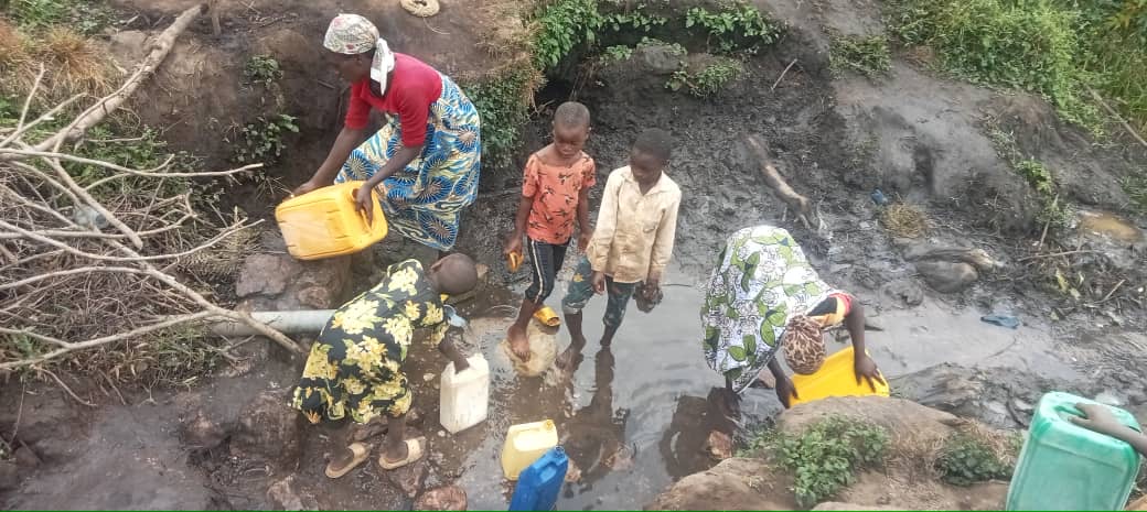 Women and children collecting water from an unsafe rural water source 1