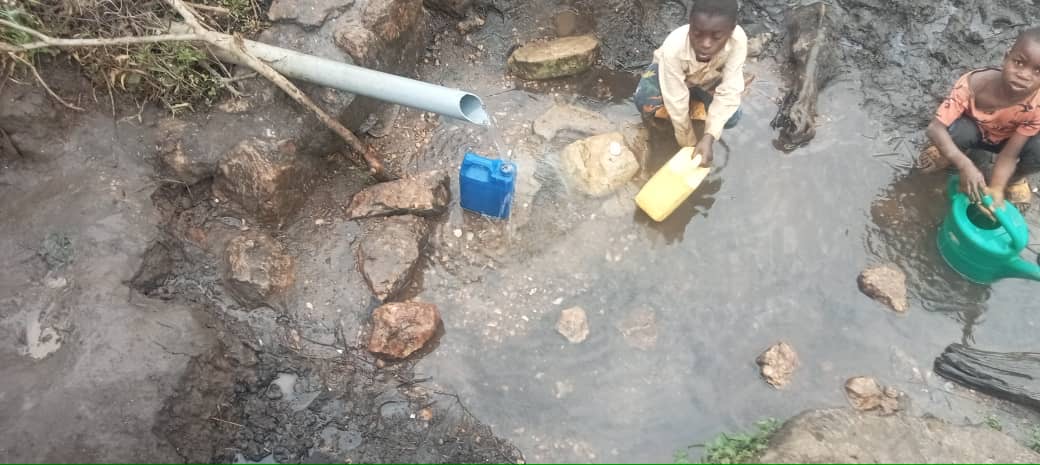 Women and children collecting water from an unsafe rural water source 2
